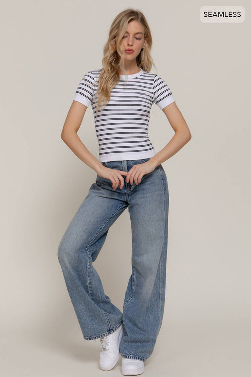 Woman wearing a striped shirt and blue jeans on a plain background