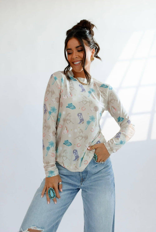 Woman wearing a patterned long-sleeve shirt and jeans against a white background