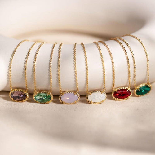 Set of gold necklaces with colorful gemstones on a white surface