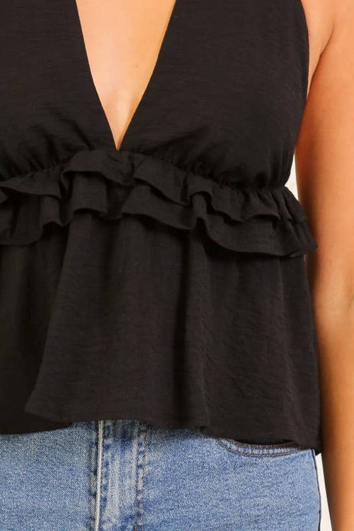 Black ruffled top worn by a person with blue jeans