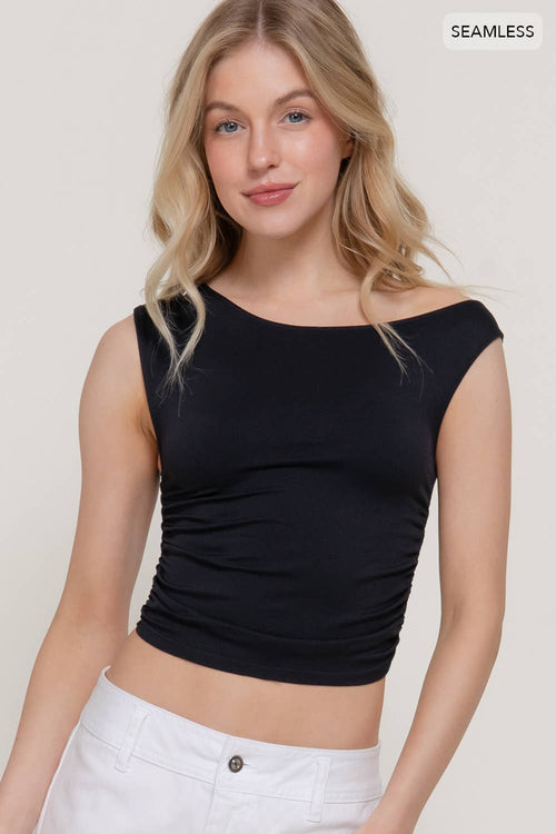 Woman wearing a black crop top and white pants on a plain background