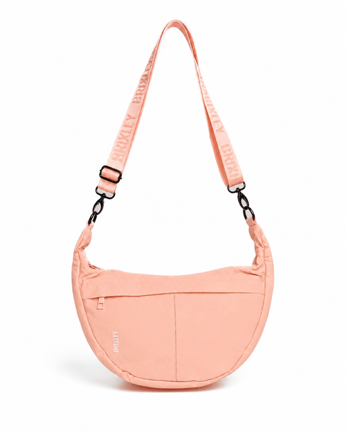 A peach-colored crescent-shaped shoulder bag with a matching adjustable shoulder strap featuring the brand name 'ALVARY' repeated, shown on a clean white background.