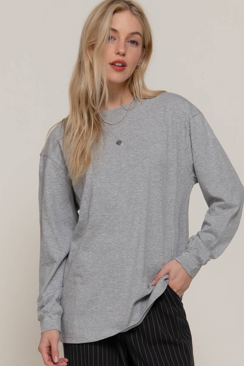 Woman wearing a gray oversized long-sleeve shirt against a plain background