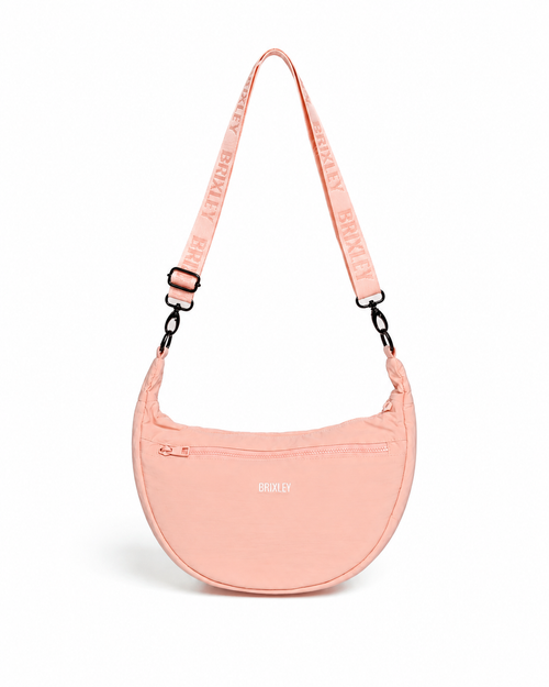 A light pink crescent-shaped shoulder bag with a matching adjustable shoulder strap featuring the brand name 'BROOKLY' in repeating text. The bag has a small white 'BROOKLY' logo on the front and is photographed against a clean white background.