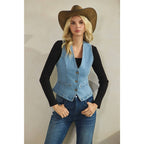 Woman wearing a denim vest, black long-sleeve shirt, and brown cowboy hat against a beige background