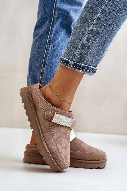 Brown slippers worn with blue jeans on a light background