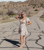 Woman in a horse dress standing on a desert road with mountains in the background
