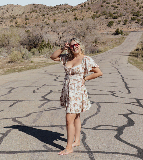 Woman in a horse dress standing on a desert road with mountains in the background