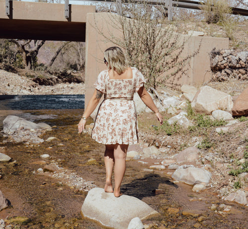 Woman in a horse dress standing by a stream with a bridge in the background