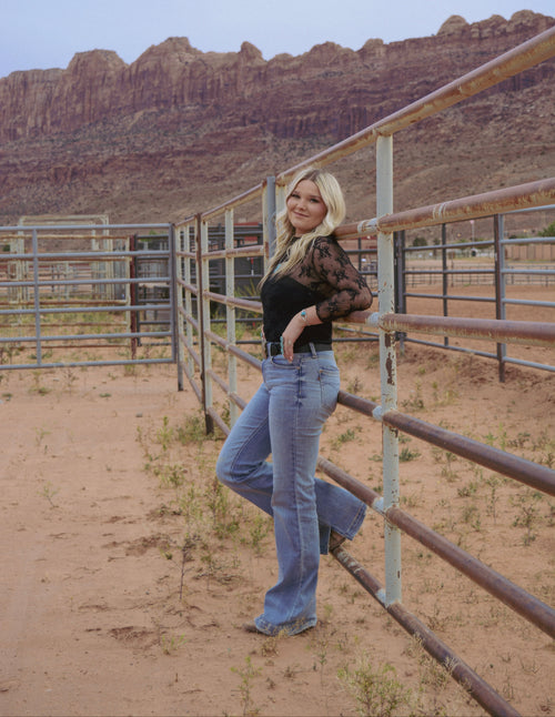 Women leaning on fence wearing boots 