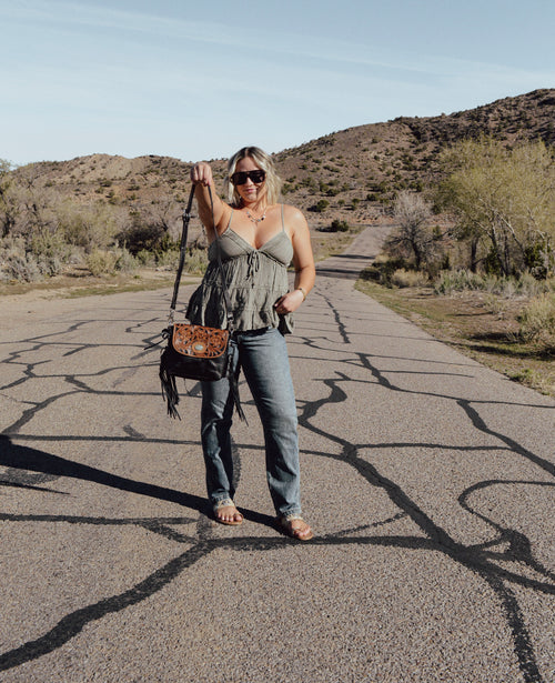 Woman standing on a desert road with mountains in the background