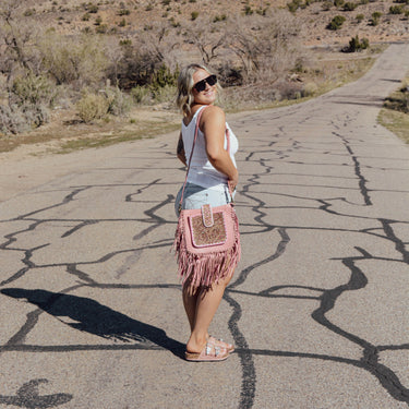 Woman standing on a desert road with mountains in the background