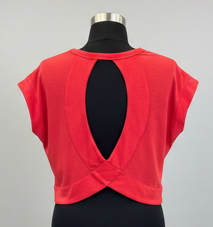 Red sleeveless top on a mannequin in a store setting with shelves in the background.