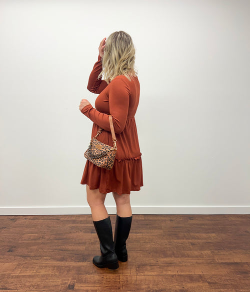 Women holding purse in orange dress and black boots with white background 