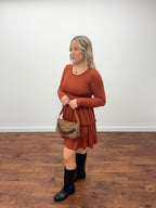 Women holding purse in orange dress and black boots with white background 