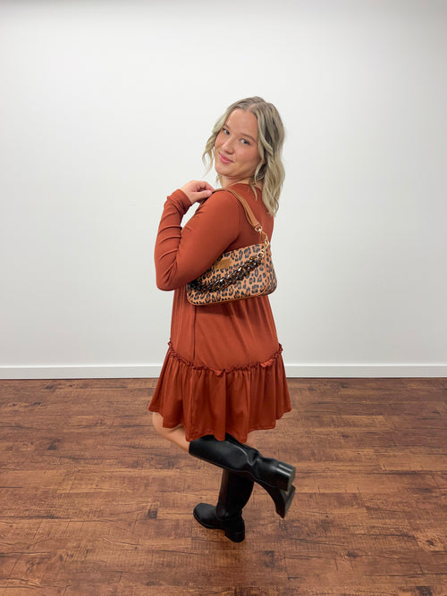 Women holding purse in orange dress and black boots with white background 