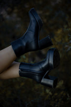 Black high-heeled boots on a blurred natural background