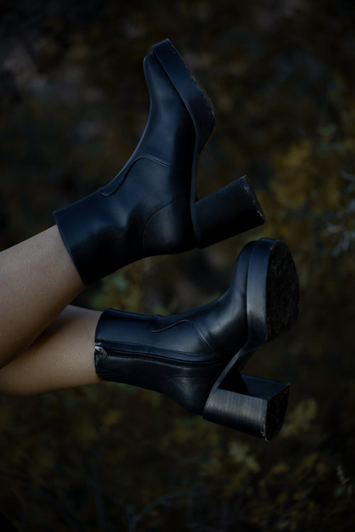 Black high-heeled boots on a blurred natural background