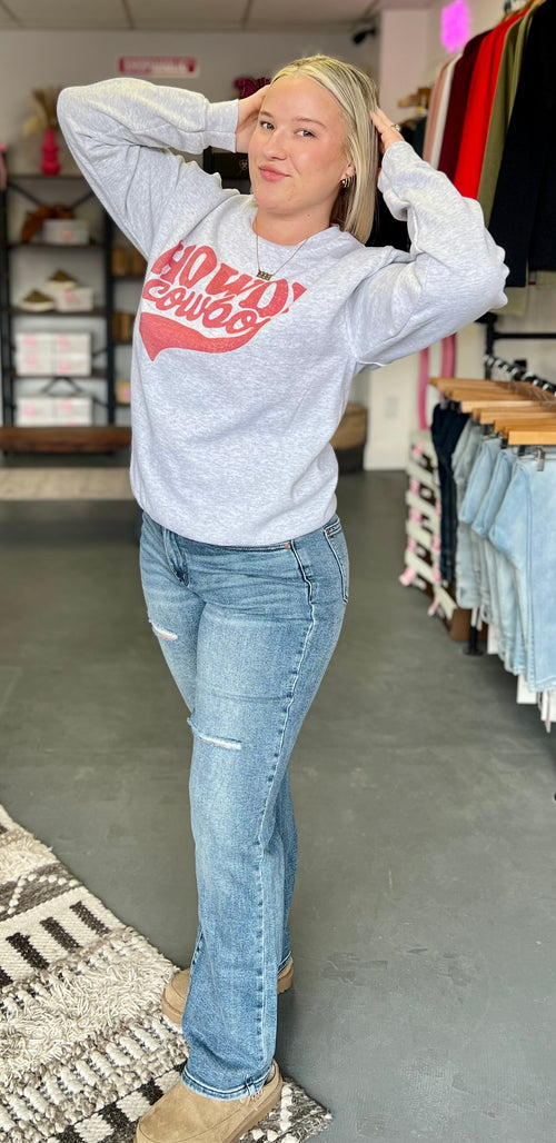 Woman wearing a gray sweatshirt with red text and blue jeans in a store setting