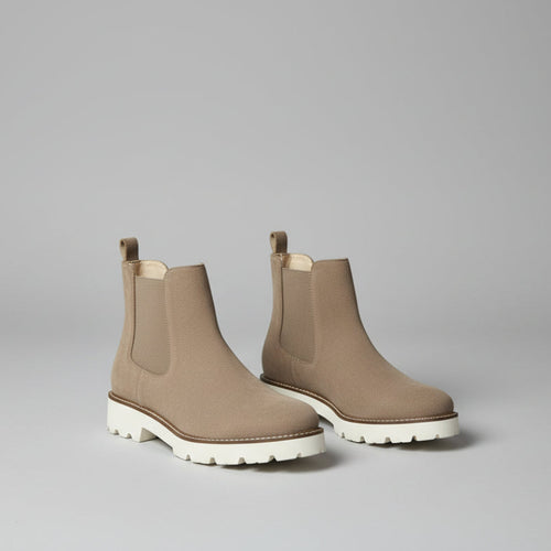 Brown Chelsea boots on a white surface 
