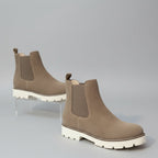 Brown Chelsea boots on a white surface 