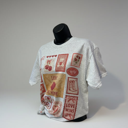 White t-shirt with red and brown graphics on a mannequin against a plain background