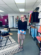 women wearing black top and shorts holding a purse in store setting 