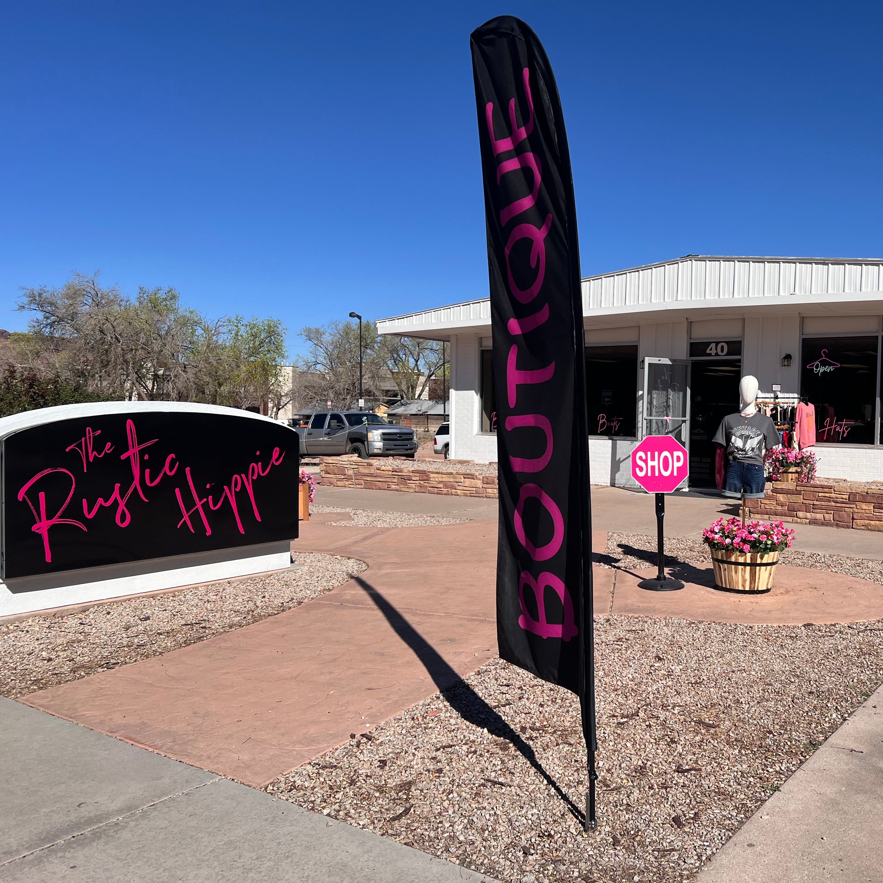 Boutique sign in front of a building with 'The Rustic Hippie' sign in the background.