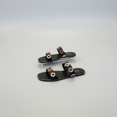 Black sandals with gold accents on a light gray background