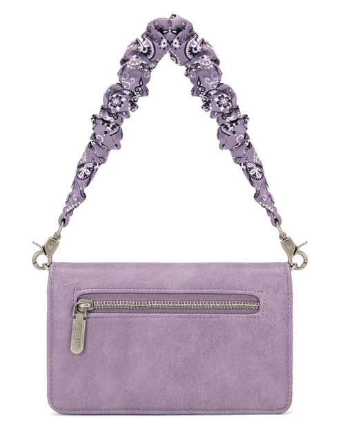 A lavender purple suede crossbody bag with a wide, ruffled shoulder strap featuring a black and white skull-and-floral print, shown on a plain white background.