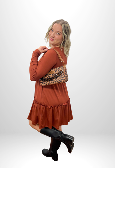 Three views of a blonde woman modeling a rust-orange long-sleeve mini dress with a pleated skirt, paired with black knee-high socks and carrying a brown woven handbag, set against a plain white studio background.