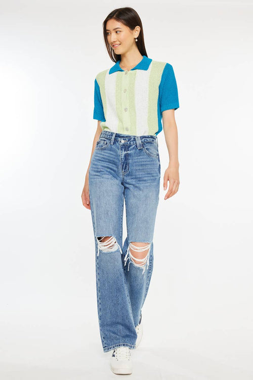 Woman wearing a colorful top and ripped jeans on a white background