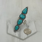 Turquoise and silver ring on a white background with a coin for scale