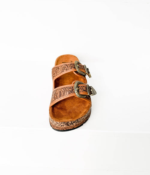 Brown sandal with decorative straps on a white background