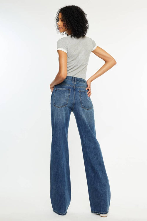 Woman wearing blue jeans and a gray t-shirt on a white background