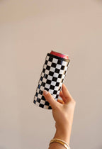 Hand holding a can with a checkered sleeve against a plain background