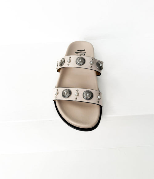 Beige sandal with decorative straps on a white background