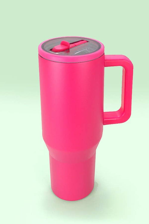 Pink travel mug with a handle on a light green background