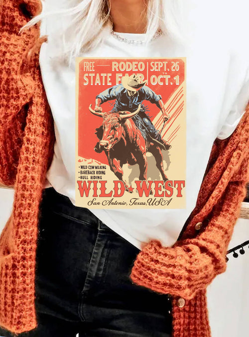 Person wearing a white t-shirt with a Wild West rodeo graphic and text, paired with an orange cardigan.