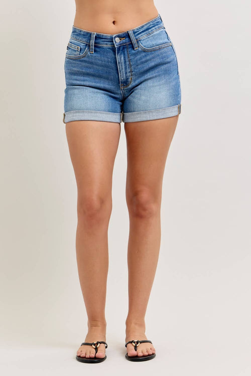 Denim shorts worn by a person on a plain background