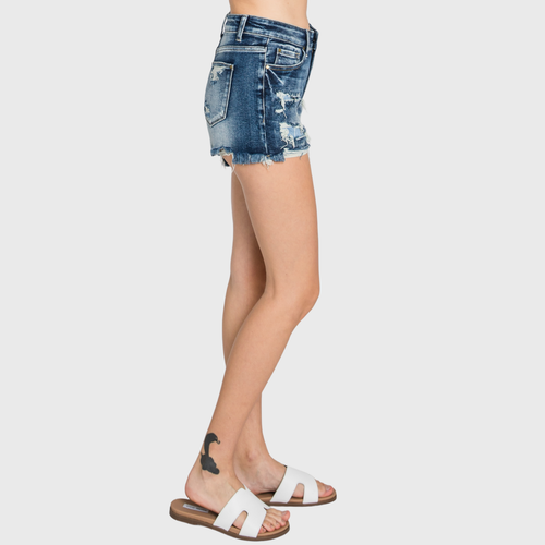 Denim shorts worn by a person on a plain background