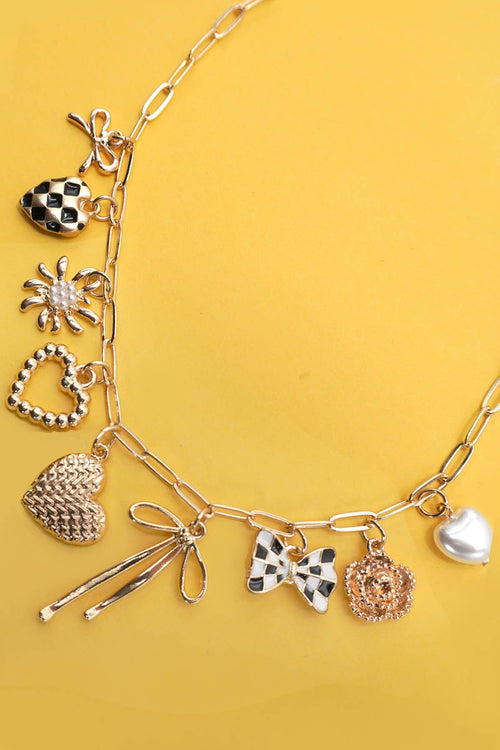 Gold necklace with various charms on a yellow background
