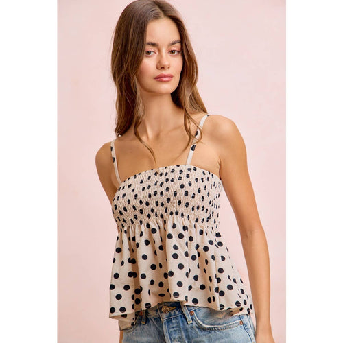 Woman wearing a polka dot top and jeans on a pink background