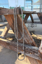 Long beaded necklace on a wooden surface with 'Randy Crow' branding.
