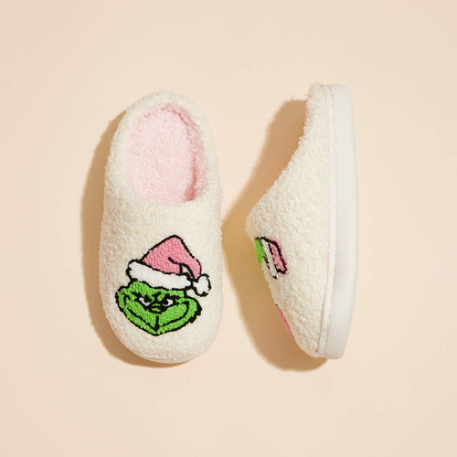 Pair of white slippers with a green face and pink Santa hat on a beige background