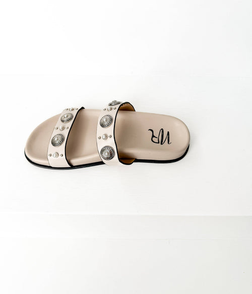 Beige slide sandal with decorative studs on a white background