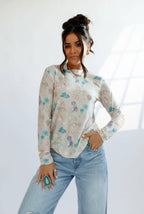 Woman wearing a patterned long-sleeve shirt and jeans against a white background
