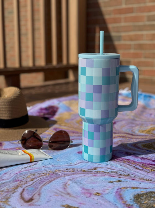 Checkered mug with handle and straw on a patterned surface