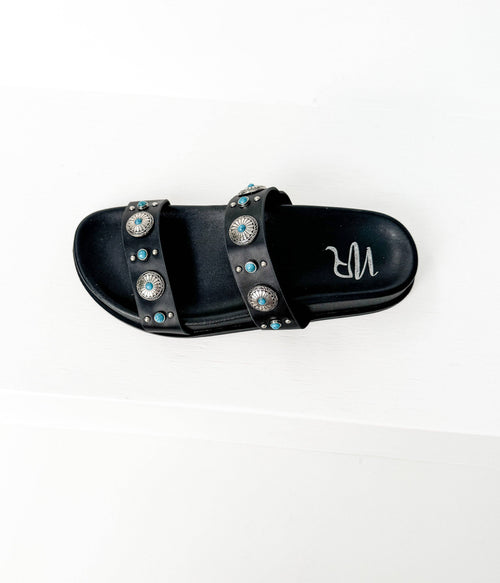 Black slide sandal with decorative embellishments on a white background