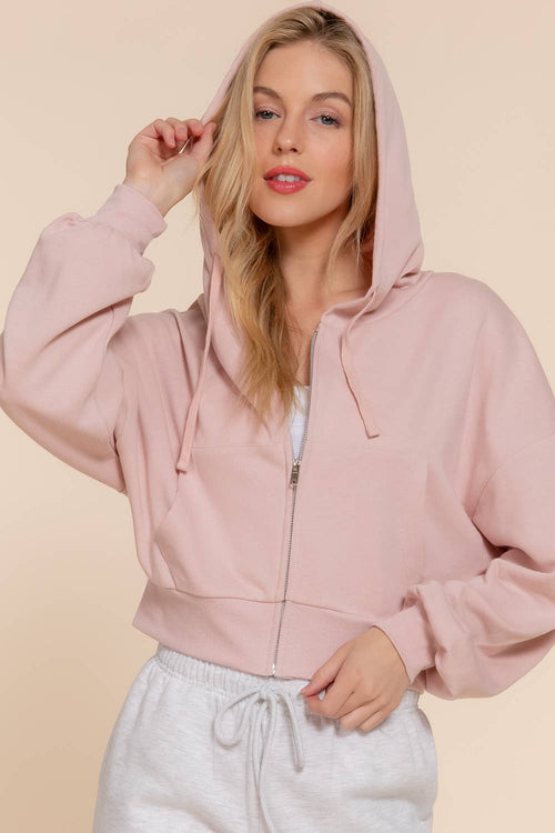 Woman wearing a pink hoodie with a beige background